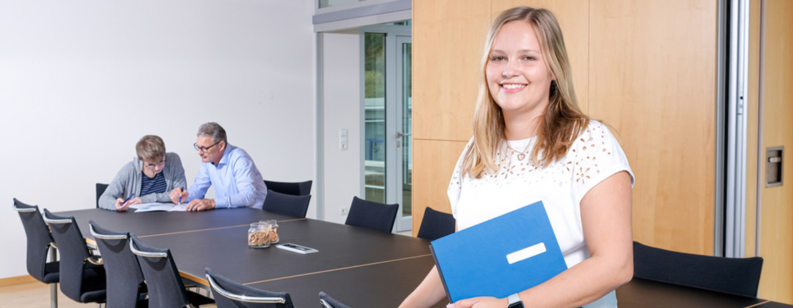 Mitarbeiterbesprechung im Büro, im Vordergrund eine junge Kollegin